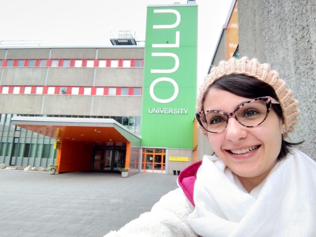 Woman smiling at the front of Oulu University