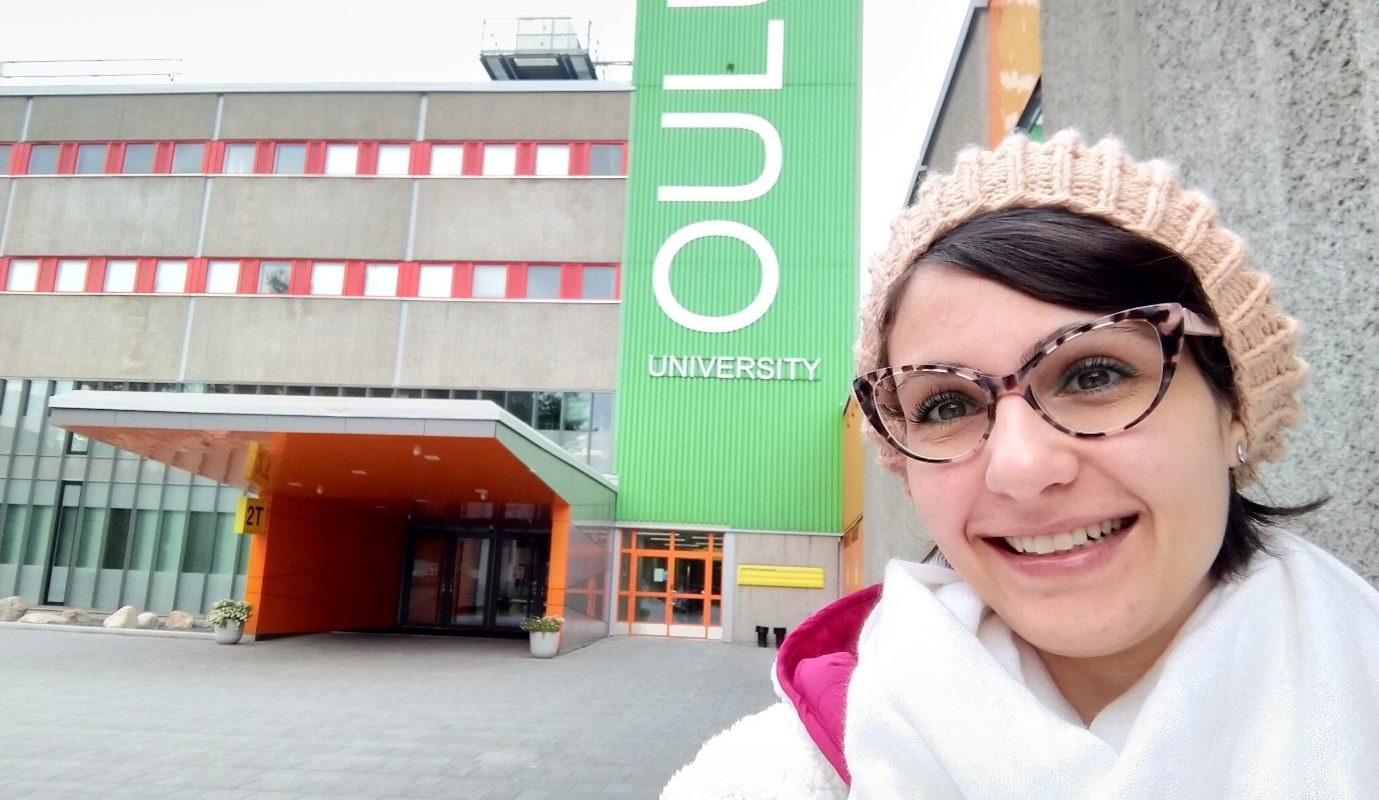 Woman smiling at the front of Oulu University