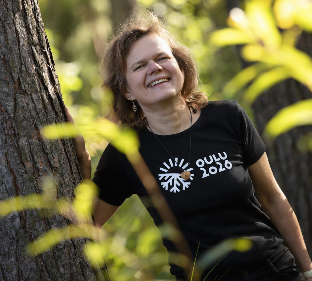 Woman smiling next to trees