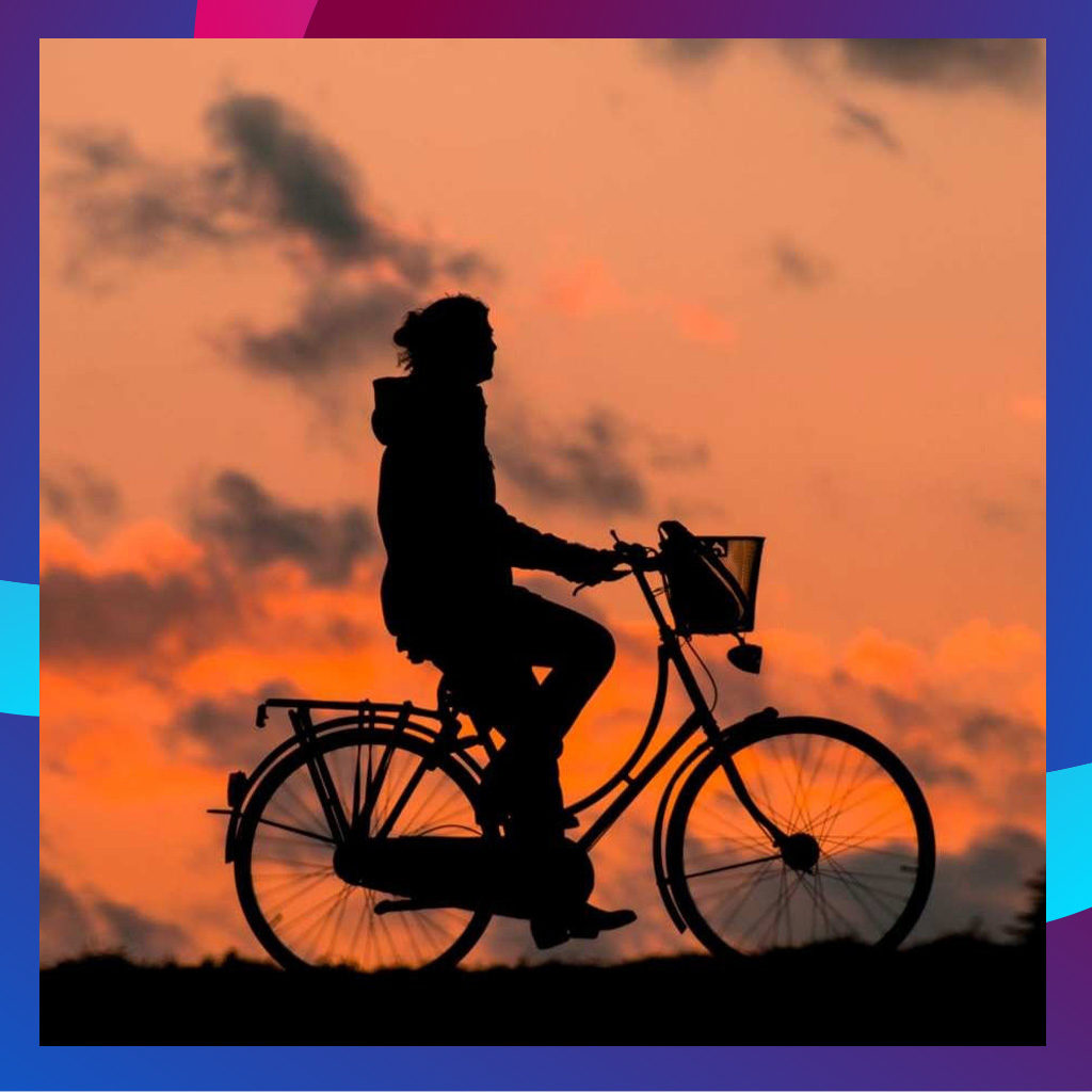 Pyöräilijä pyöräilee auringonlaskussa, ja hänestä näkyy siluetti.