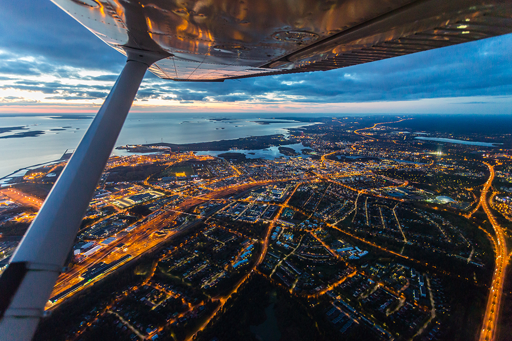 Oulun keskusta kuvattuna lentokoneesta illalla, jolloin katuvalot näkyvät.